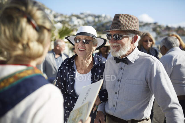 Active senior tourist couple talking with tour guide — Stock Photo