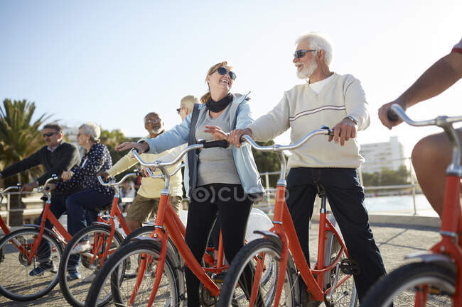 Amici turistici anziani attivi in bicicletta sul lungomare soleggiato — Foto stock
