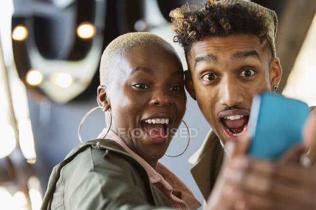 Juguetona joven pareja tomando selfie con cámara de teléfono - foto de stock