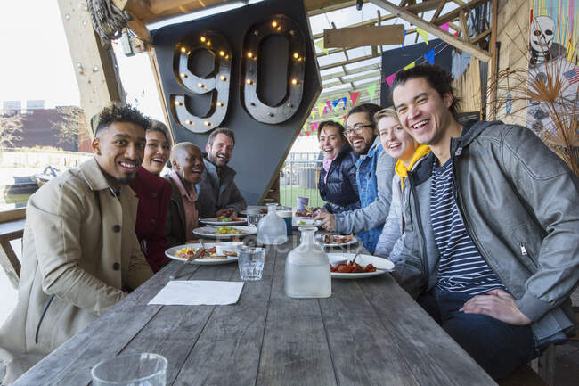 Retrato sonriendo amigos comiendo en el restaurante patio al aire libre - foto de stock