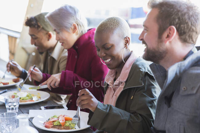 Усміхнена молода жінка обідає з друзями — стокове фото