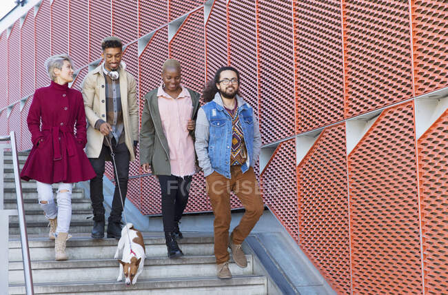 Young friends walking down down urban, modern stairs — Stock Photo