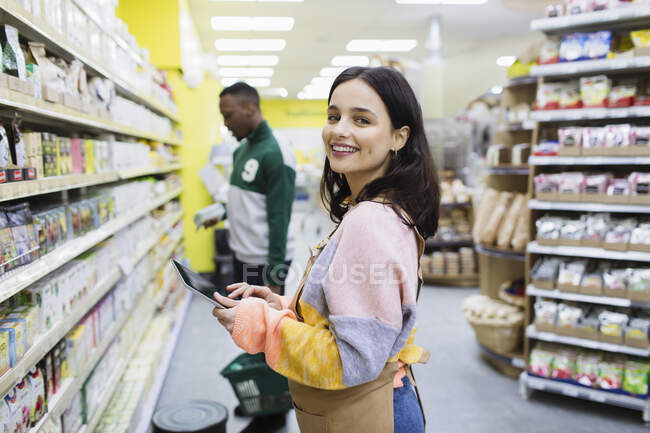 Portrait smiling, confident female grocer with digital tablet working in supermarket — Stock Photo