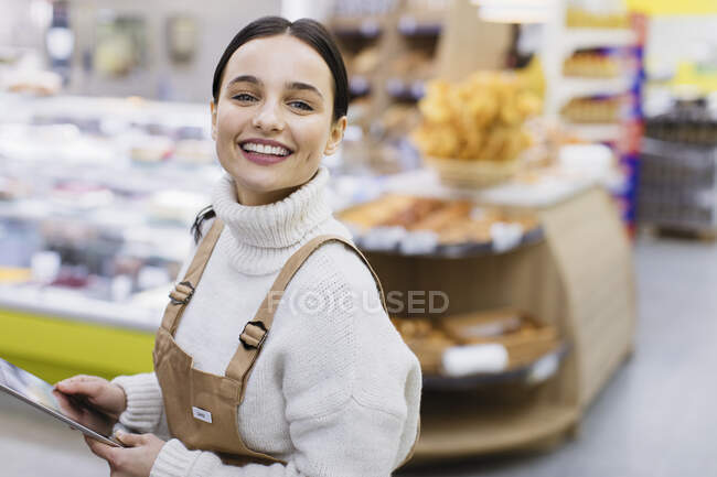 Retrato feliz, tendero femenino seguro con tableta digital que trabaja en el supermercado - foto de stock