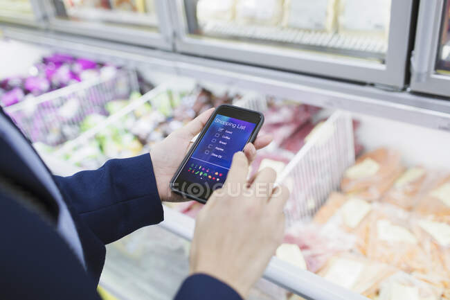 Mujer usando la aplicación de lista de compras, compras en el supermercado - foto de stock