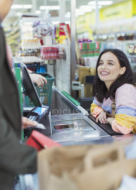 Дружелюбна жінка - касир допомагає клієнтам у супермаркеті. — стокове фото