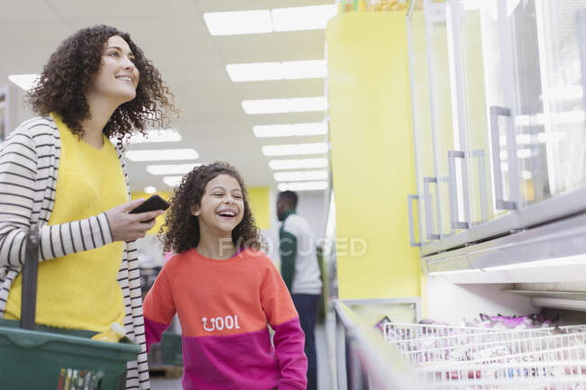 Счастливая мать и дочь покупают замороженные продукты в супермаркете — стоковое фото