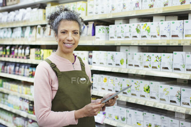 Portrait souriant épicerie féminine avec tablette numérique travaillant dans un supermarché — Photo de stock