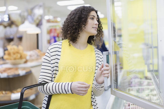 Mulher compra alimentos congelados no supermercado — Fotografia de Stock