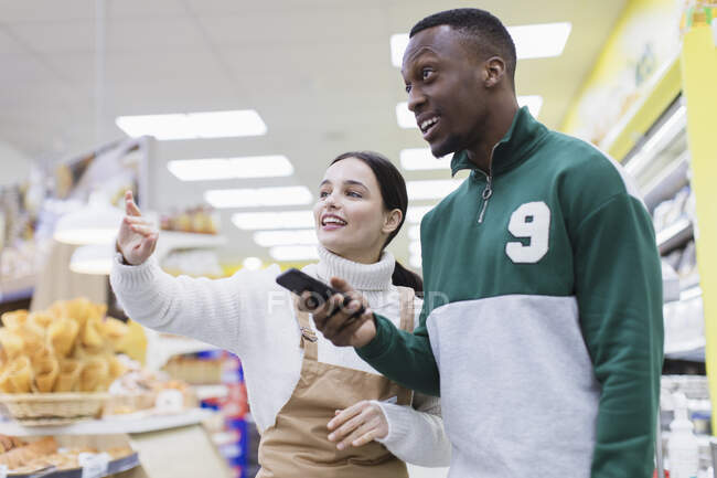 Mujer tendero ayudando al cliente en el supermercado - foto de stock