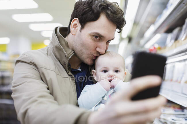 Любящий отец и маленькая дочь делают селфи в супермаркете — стоковое фото