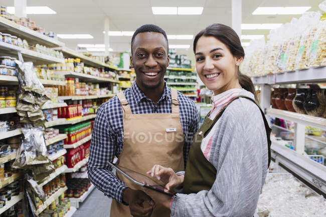 Porträt lächelnde, selbstbewusste Lebensmittelhändler mit digitalem Tablet im Supermarkt — Stockfoto