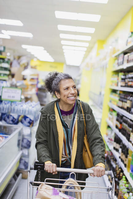 Mujer sonriente de compras en el supermercado - foto de stock