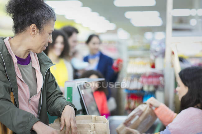 Caissier aidant le client à la caisse du supermarché — Photo de stock