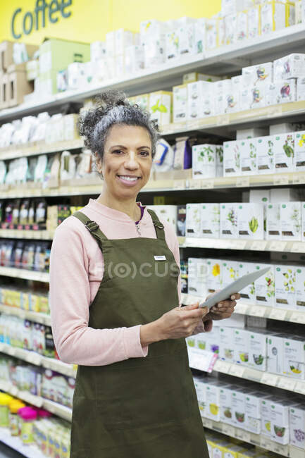 Porträt lächelnde, selbstbewusste Lebensmittelhändlerin mit digitalem Tablet im Supermarkt — Stockfoto