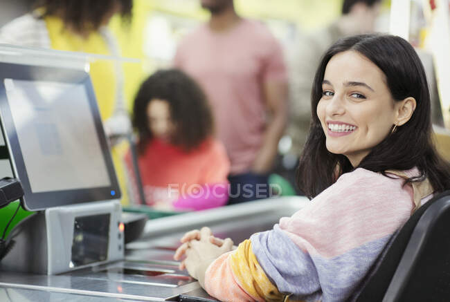 Retrato sorridente, confiante caixa feminina trabalhando no checkout do supermercado — Fotografia de Stock