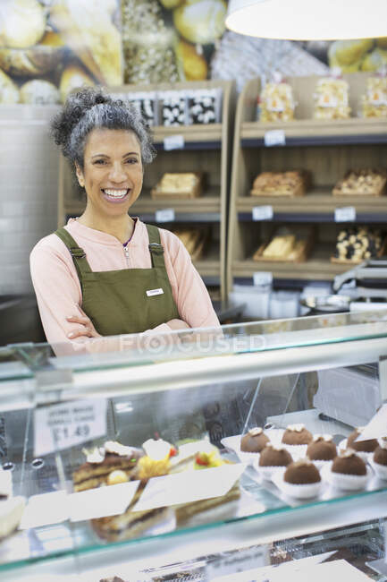 Retrato sonriente, mujer trabajadora segura detrás de vitrina en el supermercado - foto de stock