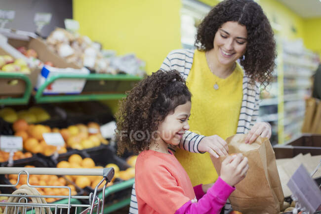 Madre e hija comprando productos en el supermercado - foto de stock