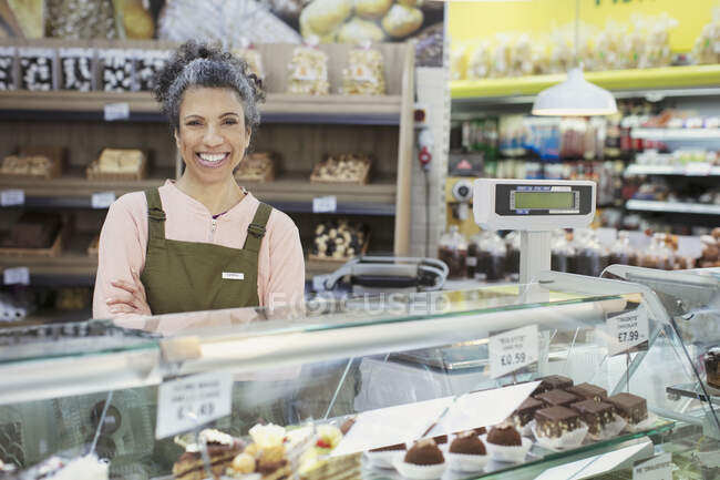 Портрет уверенной работницы за витриной пекарни в супермаркете — стоковое фото