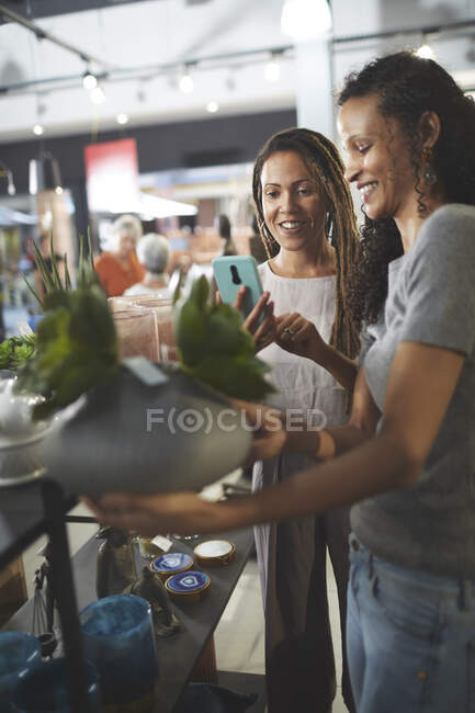 Femmes utilisant un téléphone de caméra dans le magasin de décoration à la maison — Photo de stock