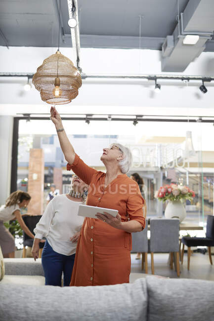 Las mujeres con la tableta digital de compras en la tienda de decoración del hogar - foto de stock