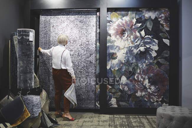 Mujer mayor de compras de alfombras en la tienda de decoración del hogar - foto de stock