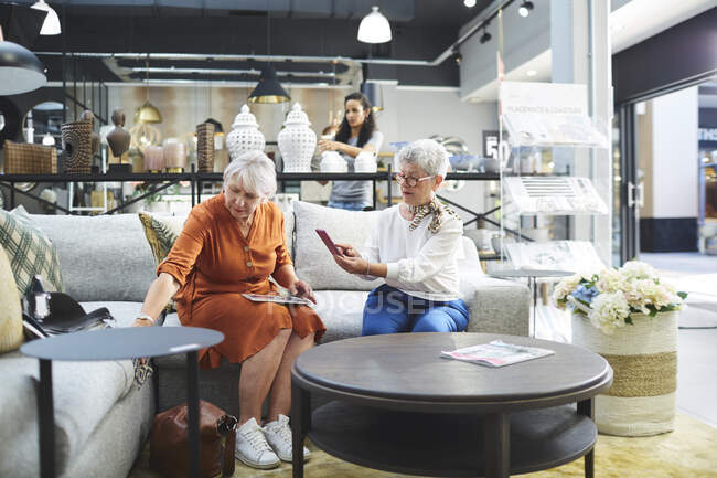 Старшие женщины покупают диван в магазине домашнего декора — стоковое фото