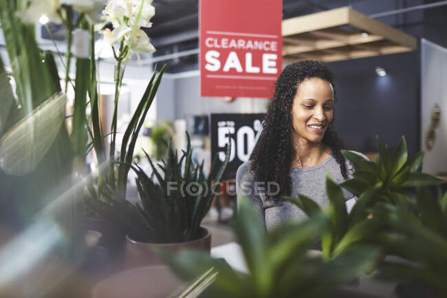 Mujer sonriente comprando plantas en la tienda de decoración del hogar - foto de stock