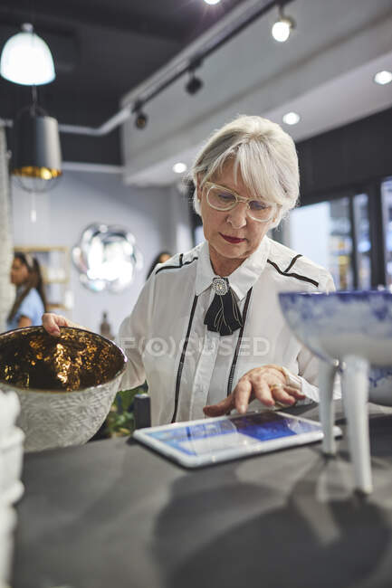 Seniorin mit digitalem Tablet arbeitet im Einrichtungshaus — Stockfoto