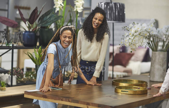 Femmes heureuses faisant du shopping pour table à manger dans le magasin de décoration à la maison — Photo de stock