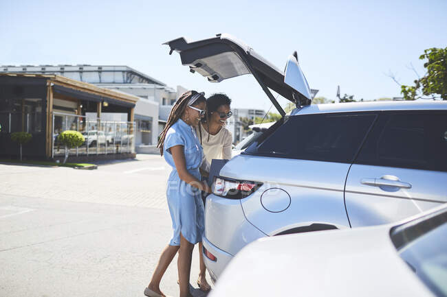Frauen laden Einkaufstüten auf sonnigem Parkplatz in Auto — Stockfoto