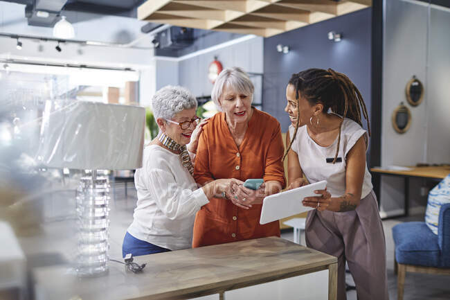 Woman helping customers shopping in home decor shop — Stock Photo