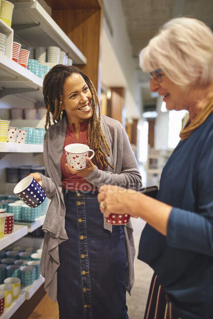 Travailleur souriant aidant femme âgée shopping pour tasses — Photo de stock