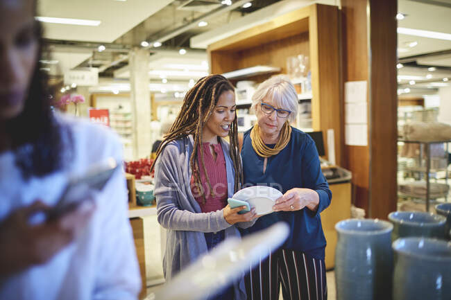 Жінки купують тарілки в магазині товарів для дому — стокове фото