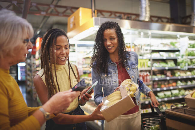 Donne con smart phone che fanno shopping al supermercato — Foto stock