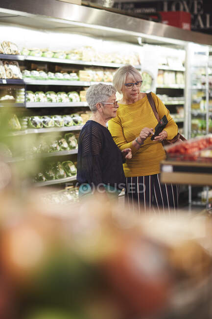 Mulheres sênior com compras de supermercado de telefone inteligente — Fotografia de Stock