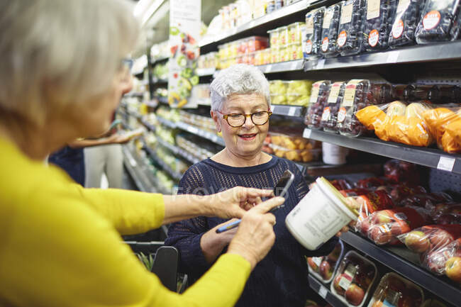 Seniorinnen mit Smartphone im Supermarkt einkaufen — Stockfoto
