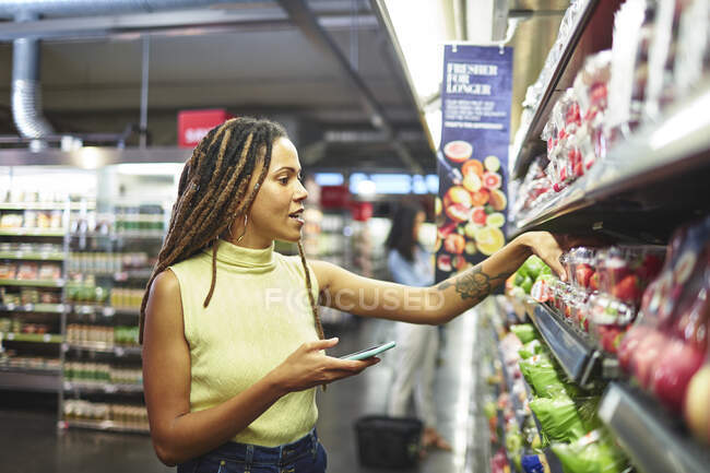 Donna con smart phone negozio di alimentari al supermercato — Foto stock