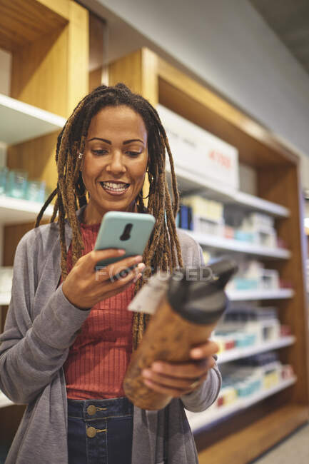Donna sorridente con smart phone shopping nel negozio di articoli per la casa — Foto stock