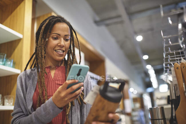 Frau mit Smartphone im Haushaltswarenladen einkaufen — Stockfoto