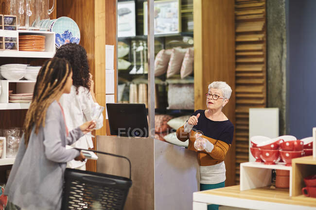 Senior cashier helping women shopping in home goods store — Stock Photo