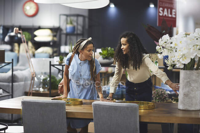 Young lesbian couple shopping for dining table in furniture store — Stock Photo