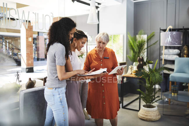 Worker helping women shopping in furniture store — Stock Photo