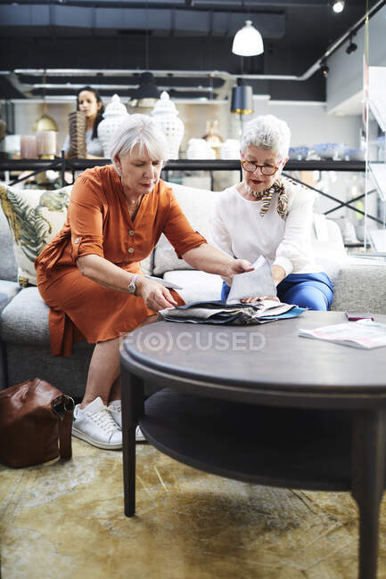 Seniorinnen betrachten Stoffmuster im Möbelhaus — Stockfoto