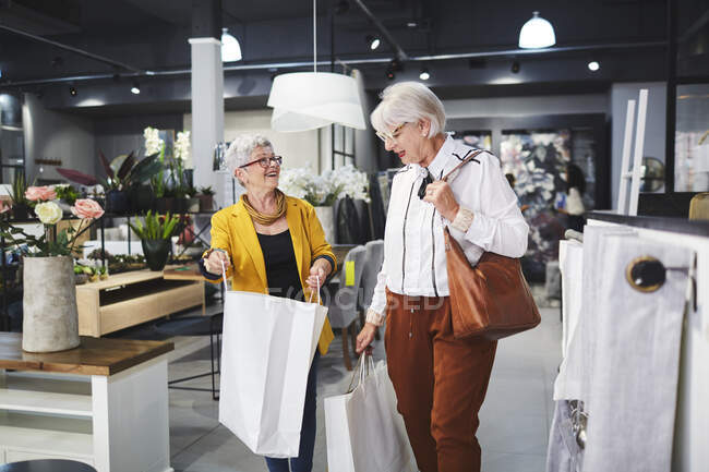 Mulheres idosas amigos saindo de casa loja de mercadorias com sacos de compras — Fotografia de Stock