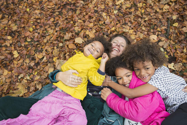 Портрет счастливая мать и дети, лежащие в осенних листьях — стоковое фото