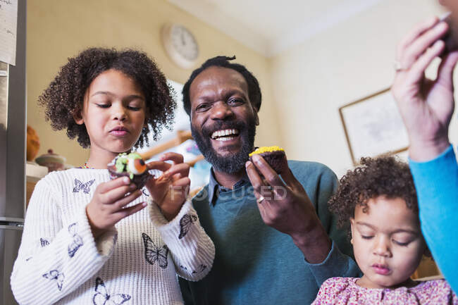 Portrait happy father and daughters eating cupcakes — Stock Photo