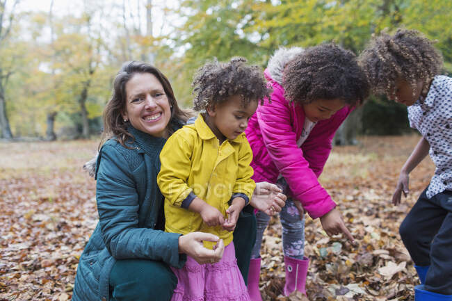 Portrait happy mother and children playing in autumn leaves — Stock Photo