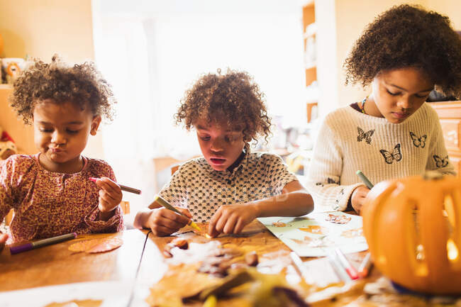 Brother and sisters making autumn crafts at table — Stock Photo