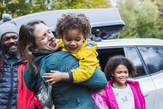 Feliz madre e hija abrazando el coche exterior - foto de stock